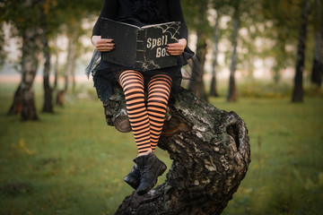 Halloween Witch with spell book in forest