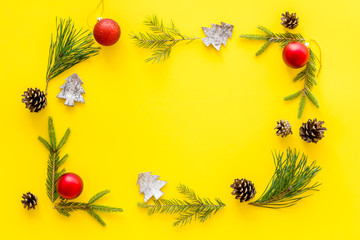 New Year decorative mockup. Fir branches and festive toys frame on yellow background top view copy space