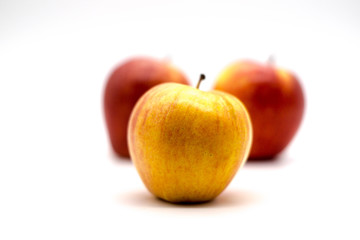 close up of a yellow apple with red apples in the background