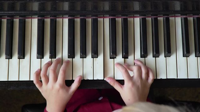 Above view of a child's fingers playing the piano keys.