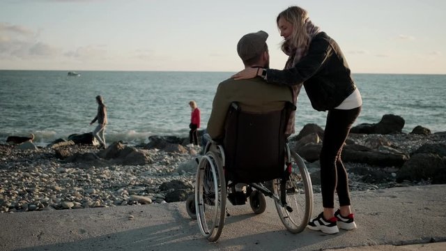 Woman is embracing her beloved disabled husband on sea shore
