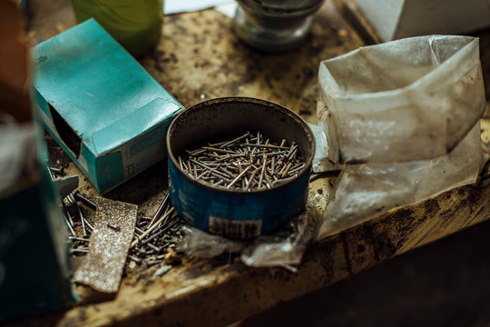 Several rusty nails inside a recycled container, on the work table of a craftsman in the footwear industry.