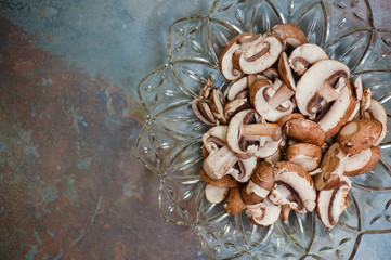 Sliced baby portabello mushrooms in vintage glass dish on slate background