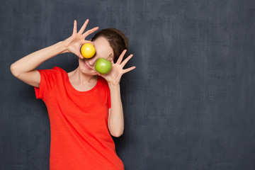 Portrait of happy woman holding ripe apples over eyes