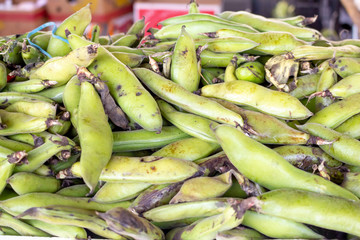 A background of fava bean pods on display at a local farmers market.