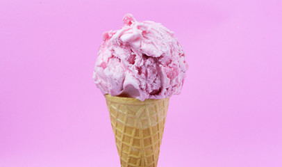 Strawberry ice cream scoop in waffle cone with  Strawberry sauce on pink background, Closeup Front view Food concept..