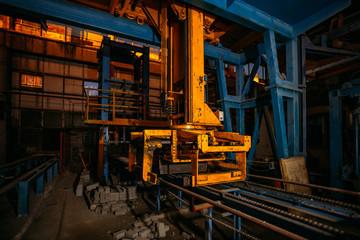Abandoned brick factory at night. Old rusty brick forming machine and conveyor illuminated by color light. Abstract industrial background