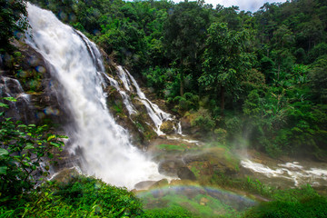 Natural blurred background of waterfalls, fast-flowing currents and water droplets from the wind blowing among the rocks and surrounded by big trees, spontaneous beauty