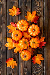 Autumn composition with red and orange leaves and pumpkins on dark wooden background top view
