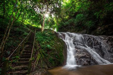Fototapeta premium Natural blurred background of waterfalls, fast-flowing currents and water droplets from the wind blowing among the rocks and surrounded by big trees, spontaneous beauty