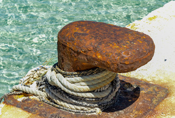 Fototapeta na wymiar Old rusting bollard by the harbourside at San Vito de Capo on the Italian island of Sicily