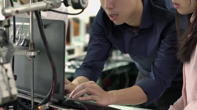 Asian engineer students are coding software with assembling and testing electric robotics arm in modern laboratory. Concept of configuration, technological developments and innovation.