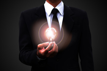 Business man black suit holding illuminated light bulb,strategy analysis concept.