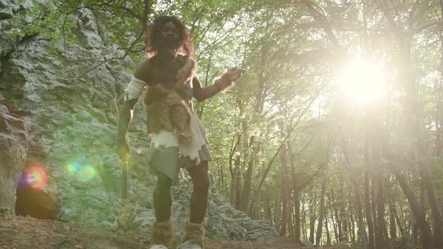 Happy african neanderthal in animal fur dancing a modern fun fance enjoying life and freedom in forest. Primitive bushman of hunter-gatherers society. Homo sapiens.