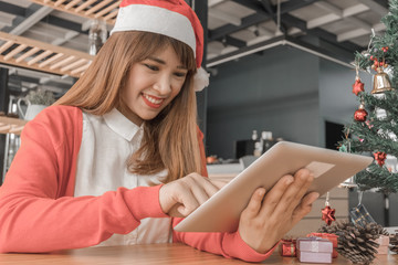 Merry christmas happy woman holding tablet for happy holidays in home, christmas concept