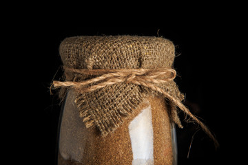 closeup rustic decorated glass jar with dried brown spices