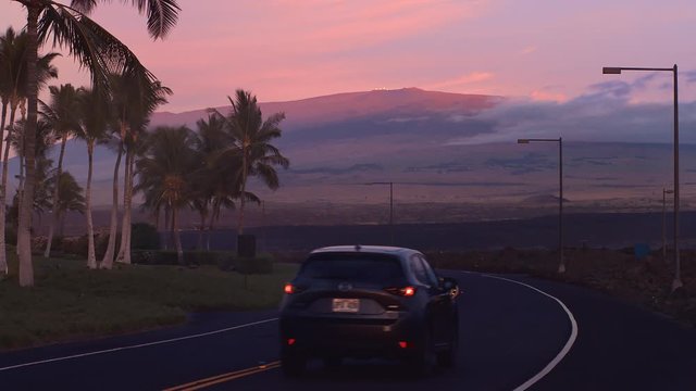 Sunset Mauna Lani Roadway to Mauna Kea Volcano Sunset with Telescopes and Mazda car on Road Hawaii