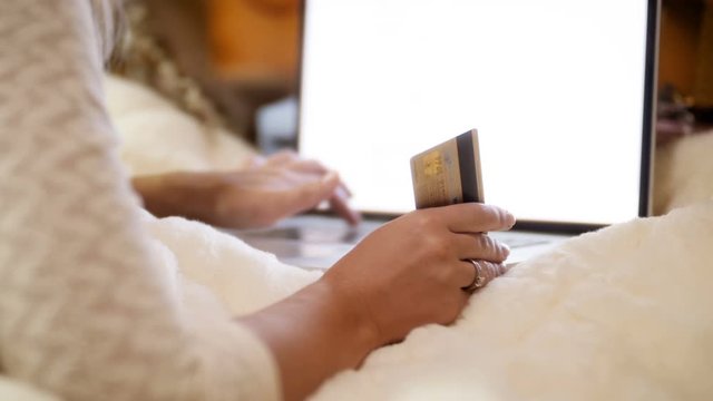 Closeup 4k footage of young woman holding credit card in hand while browsing intrnet and online stores. Concept shot of online shopping and e-commerce.