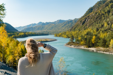 Autumn woman standing backwards and watching nature. Autumn nature colors with woman back view.