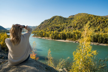 Autumn woman sitting backwards and watching nature. Autumn nature colors with woman back view.