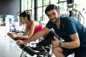Obraz premium Young couples work out at the gym to strengthen the body. Each person recommends exercise for each other and encourage each other while exercising.