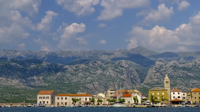 Small fishing village below mountains, coastal town in Dalmatia, Croatia, rolling clouds time lapse of Vinjerac and Velebit mountain in the background