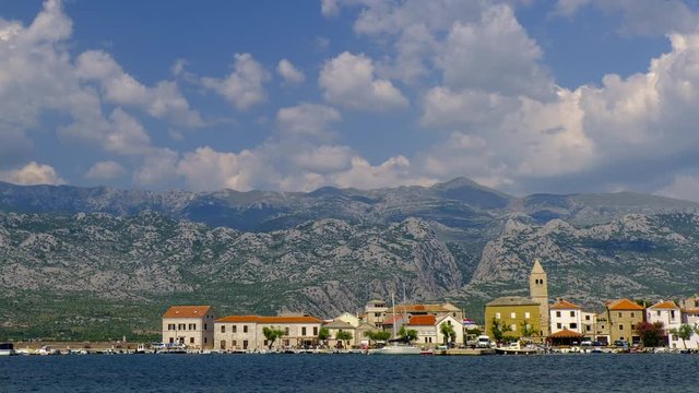 Time lapse of small village and harbor at seaside, mountains and clouds in the background, Vinjerac, Croatia, travel and cityscape, zoom out revealing shot