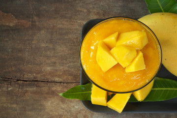 Top view Mango smoothie in glass with slices of mango fruit on wooden background. Taste sweet, tasty, drink for healthy