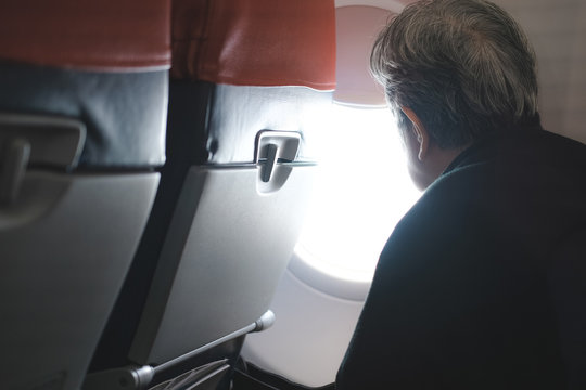 elderly old elder senior woman looking through airplane window