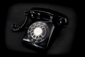old fashioned  black rotary telephone on a black background