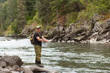 Fly fisherman casting in the mountain stream during the fall season.