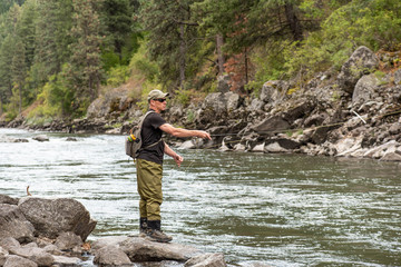 Fly fisherman casting in the mountain stream during the fall season.