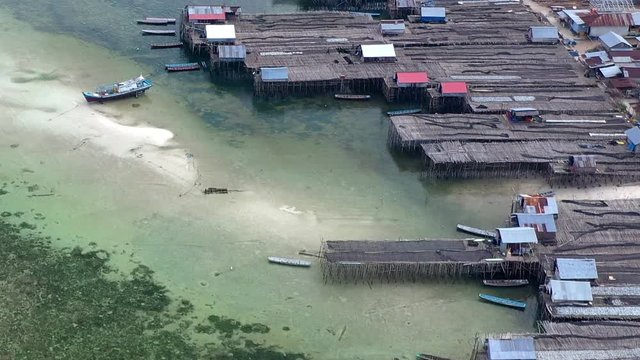 Aerial Drone Video flying above Fishing Village of Tanjung Binga in Belitung Island Indonesia. Fishing Boat on Clear water, village houses