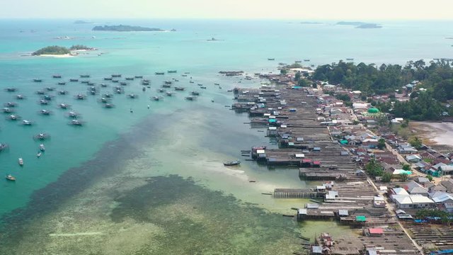 Aerial Drone Video flying above Fishing Village of Tanjung Binga in Belitung Island Indonesia. Fishing Boat on Clear water, village houses