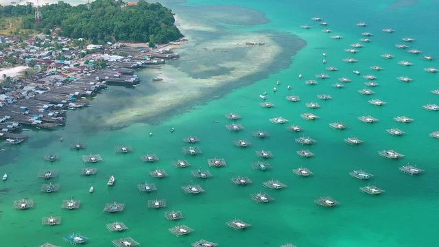 Aerial Drone Video flying above Fishing Village of Tanjung Binga in Belitung Island Indonesia. Fishing Boat on Clear water, village houses
