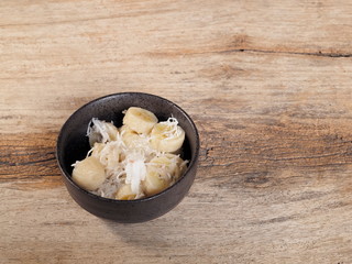 view of Khanom kluay in a dish on wood texture background, Thai dessert local food made of ripe banana mixed coconut and sugar.