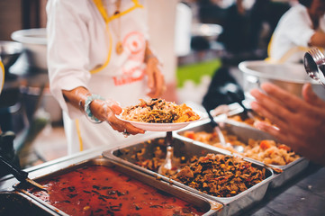 Homeless people receive free charity food from the hands of volunteers : concept of hunger problems in a helping society