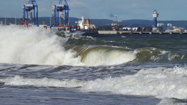 Container Terminal Cranes on Baltic Sea with Heavy Waves Splashing into Shore