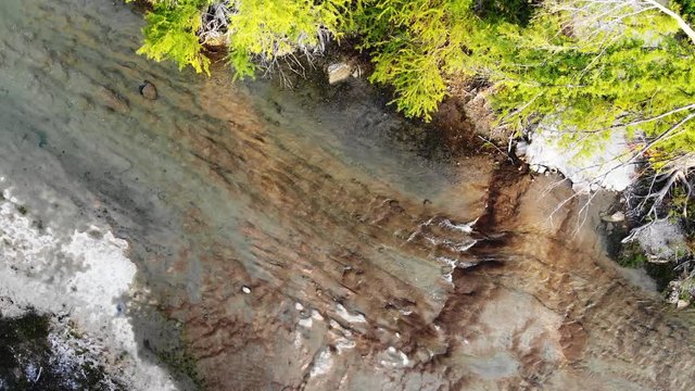 Aerial - high above top down view of the river where water is breaking into 3 strands forming small waterfalls; rotating CCW
