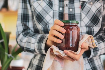person hand holding a homemade jar of jam with fruits, glass pot