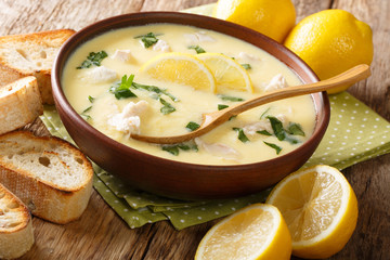 Hot greek lemon soup with chicken close-up in a bowl with bread. horizontal