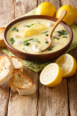 Homemade egg lemon soup with chicken and orzo pasta close-up in a bowl. vertical