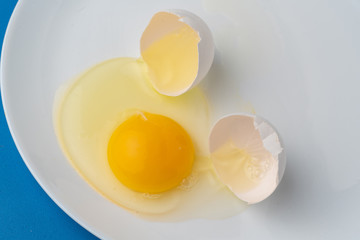 a broken white egg in the plate to prepare some food dishes