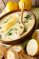 Greek lemon soup Avgolemono served with toasted bread close-up in a bowl. vertical
