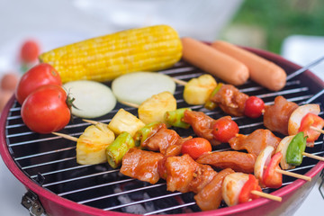 Colorful BBQ Grilling with pork ,sausage,tomato,onion,pineapple,chilli and corn on portable barbecue outdoor.