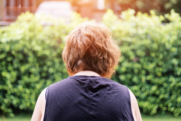 Back view of chubby woman in the garden with green leaves trees background.