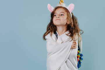 Little girl in noble stance wearing unicorn headband, wrapped in bed cover © zzzdim