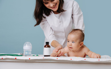 Doctor massaging infant baby on a special table over blue background