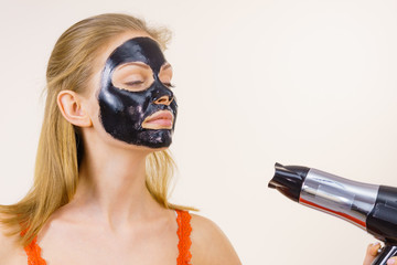 Girl drying peel-off black mask on face
