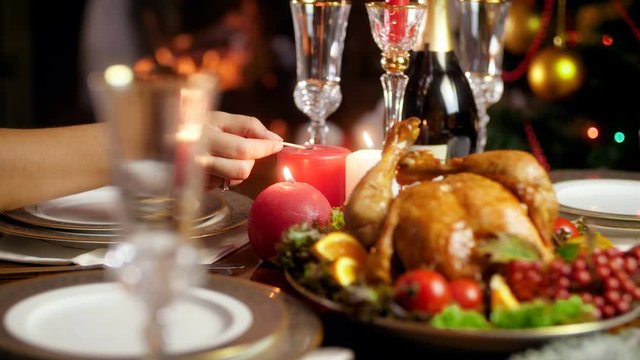 4k video of woman lighting up candles on table served for Christmas or New Year dinner. Dining table served for big family on winter holidays and celebrations.